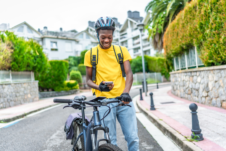 Young delivery man using phone to check the location